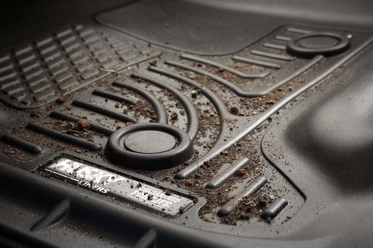 HUSKY LINERS X-ACT AXS floor liners for Dodge Ram 3500 Crew Cab, with dirt and mud on textured black plastic surface.